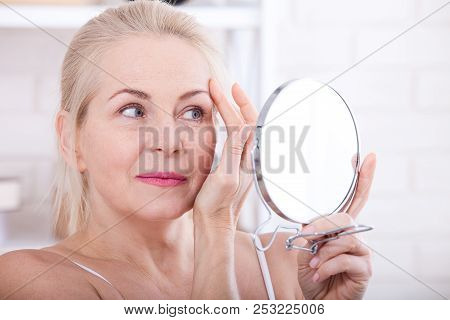Forty Years Old Woman Looking At Wrinkles In Mirror. Plastic Surgery And Collagen Injections. Makeup