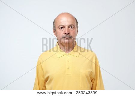 Elderly Man Emotions, Portrait Of Serious Senior Caucasian Man Looking At Camera Against Gray Wall
