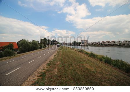 Dyke Along River Hollandsche Ijssel With The City Of Ouderkerk On The Background In The Netherlands.