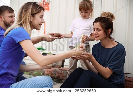 Poor People Receiving Food From Volunteers Outdoors
