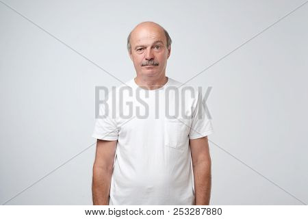 Elderly Man Emotions, Portrait Of Serious Senior Caucasian Man Looking At Camera Against Gray Wall