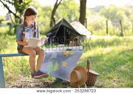Little Girl With Map And Book Near Tent Outdoors. Summer Camp