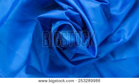 Blue Synthetic Lining Fabric With Folds. Crumpled Sheet Or Clothes Background,