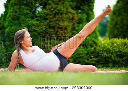 Expectant Woman Performing Side Reclining Leg Lift On Yoga Mat