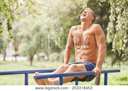 People, Sport, Motivation Concept. Handsome Muscular Male Does Exersices Outdoor Early In Morning, W
