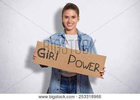 Indoor Shot Of Beautiful Woman Belongs To Feminism Movement, Has Cheerful Expression, Holds Plate Wi