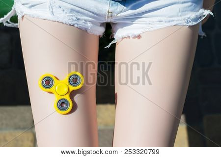 Concept Of Way Of Spending Free Time. Top View Photo Of Fidget Spinner Lying On Girl's Knee