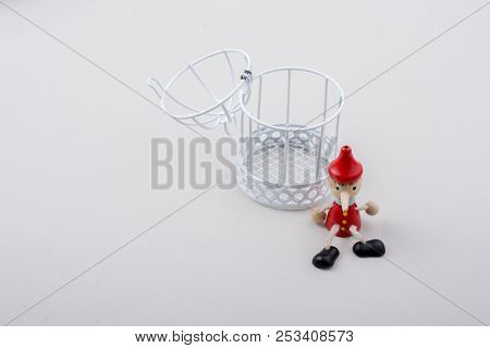 Metal Cage And Little Puppet Pinocchio Made Of Wood