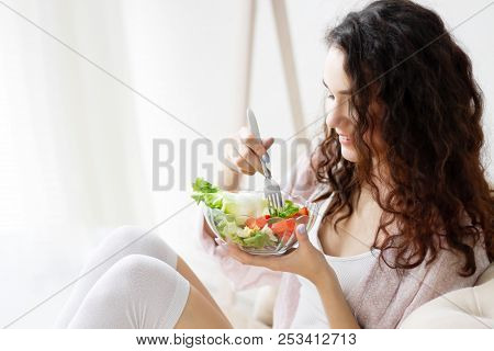 Young Girl Woman Female Wear Pajams Sleepwear, White Top And Stockings Sitting On Sofa And Eating Ge