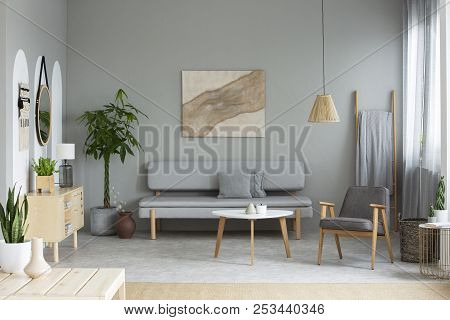 Real Photo Of Grey Sitting Room Interior With Modern Poster, Lounge With Cushions, Armchair By Woode