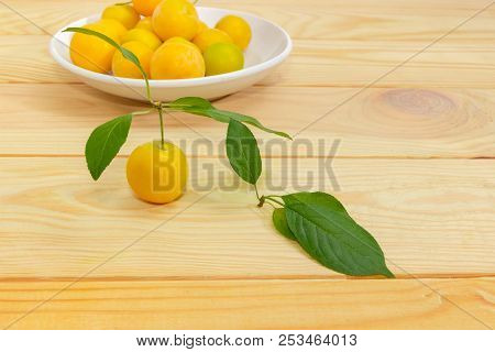 One Yellow Cherry Plum With Leaves At Selective Focus On A Blurred Background Of Saucer With Other C