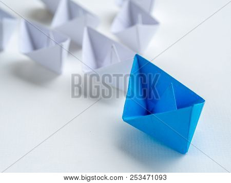 Leadership Concept. Blue Paper Ship Lead Among White. One Leader Ship Leads Other Ships.