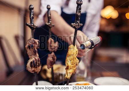 Meat On Skewer Fry With A Cooking Gas Torch Flomber. Preparation Of Delicious Fresh Meat Frying With