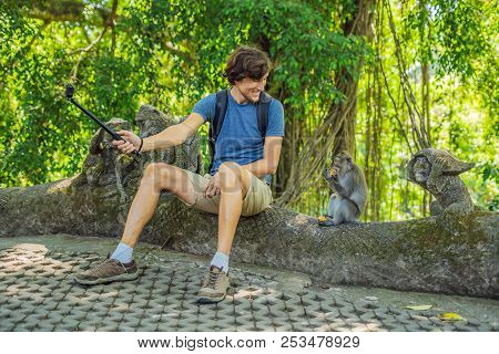 Selfie With Monkeys. Young Man Uses A Selfie Stick To Take A Photo Or Video Blog With Cute Funny Mon