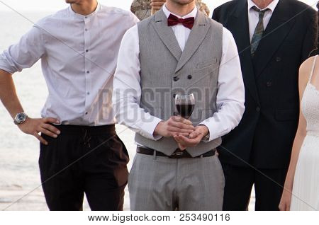 A Happy Groom In A Gray Suit With A Cage And A Red Butterfly Is