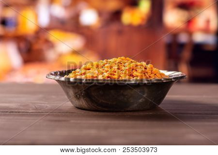 Lot Of Whole Raw Red Lentils In Old Iron Bowl With Rustic Wood Kitchen In Background