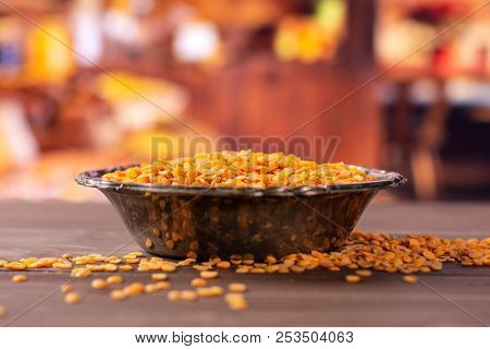 Lot Of Whole Raw Red Lentils In Old Iron Bowl With Rustic Wood Kitchen In Background