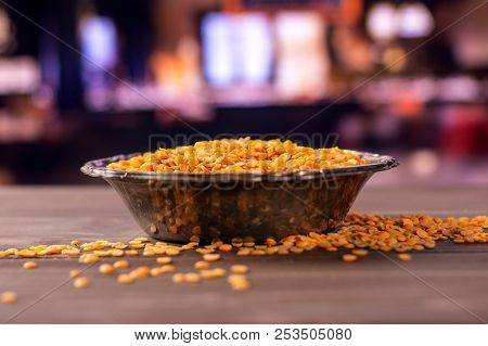 Lot Of Whole Raw Red Lentils In Old Iron Bowl With Restaurant In Background