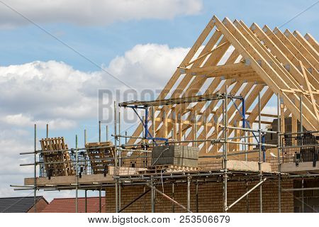 Construction Industry. Timber Framework Of House Roof Trusses With Scaffold On A Building Being Buil
