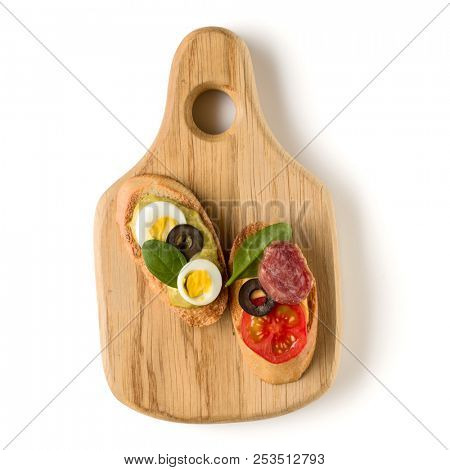 Open faced sandwich canape or crostini on a wooden serving board isolated on white background closeup. Top view.