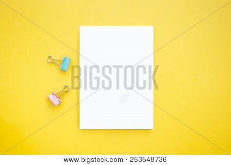 Notepad And Binder Clips On Bright Yellow Background With Copyspace.