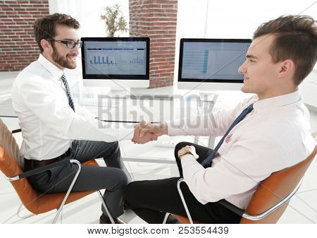 handshake colleagues sitting at your Desk