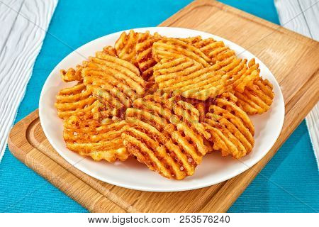Crispy Potato Waffles Fries, Wavy, Crinkle Cut, Criss Cross Fries On A White Plate On A Cutting Boar