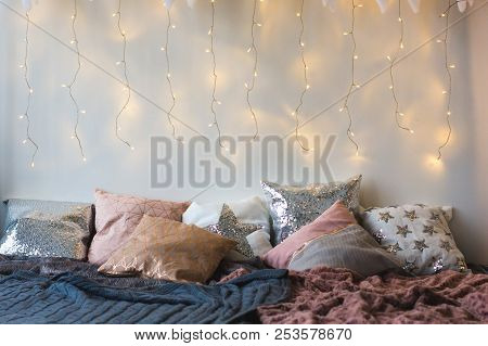 Xmas In Morning Bedroom. Double Bed In Christmas Interior On White Wall Background With Cozy Lights.