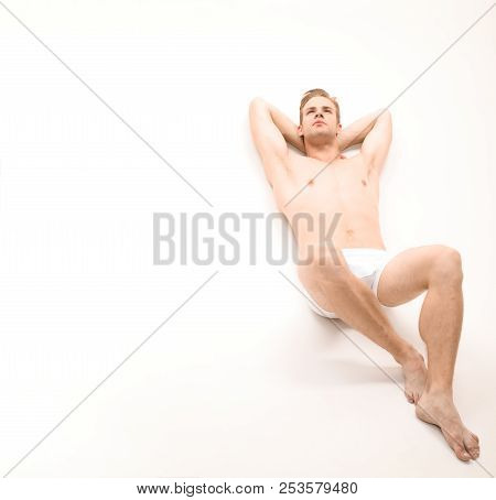 Handsome Sexy Naked Man Lying On White Background. Sexy Man In Underwear. Muscular Male Model In Tre