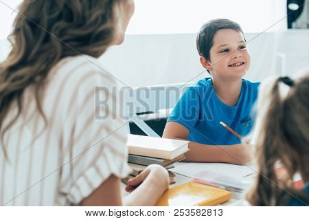 Partial View Of Mother And Kids Doing Homework Together At Home