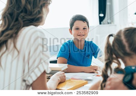 Partial View Of Mother And Kids Doing Homework Together At Home