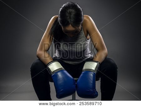 Black female wearing boxing gloves looking angry as a boxer, MMA fighter or self defense trainer sit
