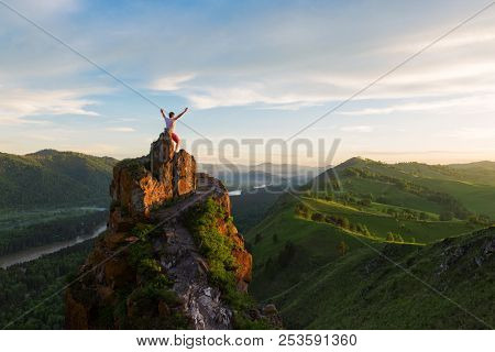 Travel, freedom leadership and real life concept - man standing on top of cliff in summer beauty sunset in Altai mountains