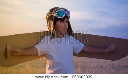 Succcess, Happy child playing with toy wings against summer sky background. Retro vintage toned. Travel and adventure concept