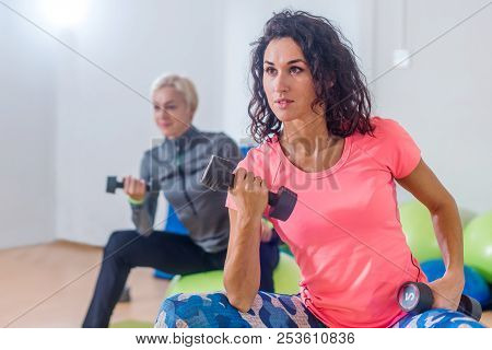 Sporty Slim Women Taking Part In Gym Fitness Class Exercising Sitting On Physioballs Doing Alternate
