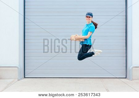 Female Delivery Worker Jumping In Front Of A Storage Warehouse