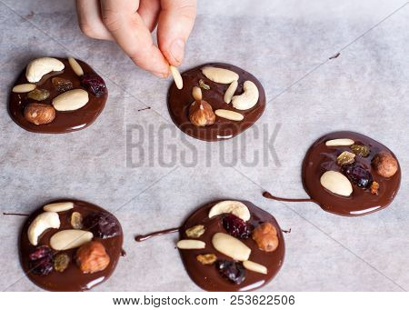 Homemade Chocolate Snacks With Nuts And Berries Preparation, Man Adding Almond To Chocolate Circles