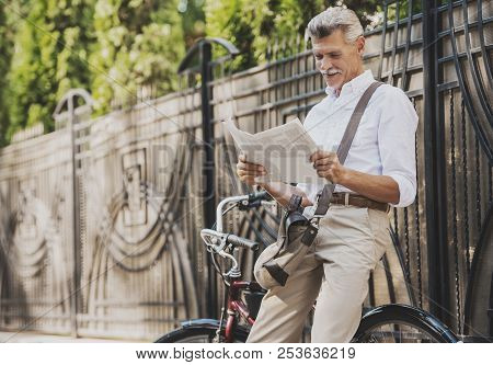 Old Man Reading Newspaper Near Bicycle In Park. Relaxing In Park. Active Rest Concept. Riding On Bic