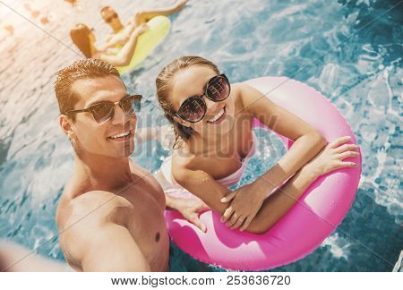Young Smiling Couple Near Swimming Pool In Summer. Leisure In Summer. Relaxation For Family Outdoor.