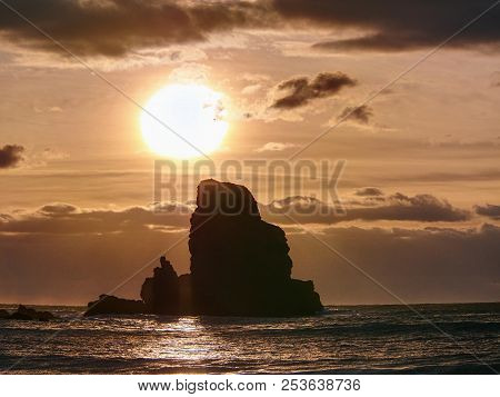Beautifully Shaped Black Boulders And A Dramatic Fiery Sunset And A Stony Beach