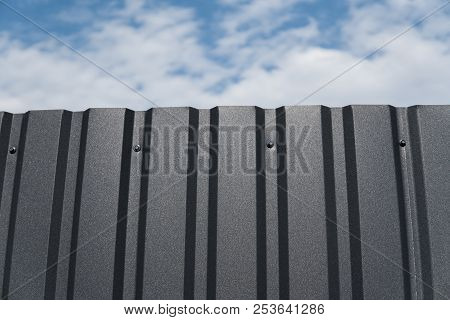 Brown Metal Plate Against Blue Cloudy Sky. Siding. Seamless Surface Of Galvanized Steel. Industrial 