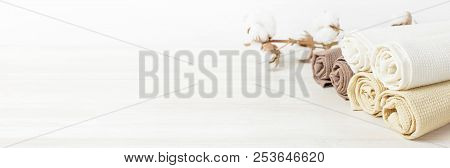 Multicolored Clean Towels With A Branch Of Cotton On A Light Wooden Background With Copy Space. Text