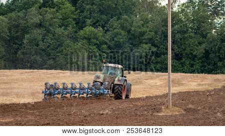 A Tractor With A Plow Treats The Soil. View From The Back.