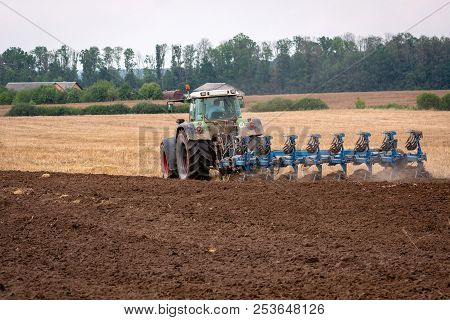 A Tractor With A Plow Treats The Soil. View From The Back.