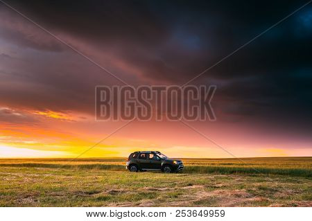 Renault Duster Or Dacia Duster Suv In Road Through Summer Wheat Field In Amazing Sunset Time.