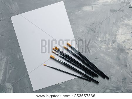 Painting Brusches, White Paper On Gray Concrete Background. Flat Lay, Top View