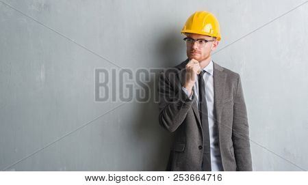 Young redhead man wearing architect outfit and helment serious face thinking about question, very confused idea