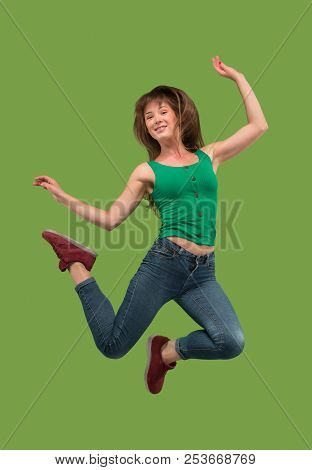 Freedom In Moving. Mid-air Shot Of Pretty Happy Young Woman Jumping And Gesturing Against Orange Stu