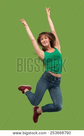 Freedom In Moving. Mid-air Shot Of Pretty Happy Young Woman Jumping And Gesturing Against Orange Stu