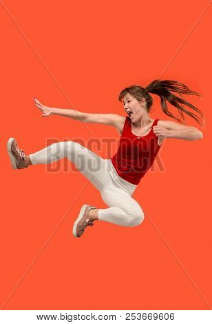 Freedom In Moving. Mid-air Shot Of Pretty Happy Young Woman Jumping And Gesturing Against Orange Stu